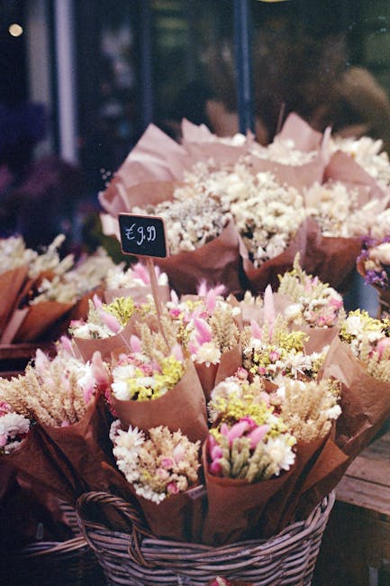 A vibrant flower arrangement display outside Stepney Florist showing a variety of fresh blooms including bright yellow sunflowers, white lilies, pink roses, purple chrysanthemums, and red tulips arran