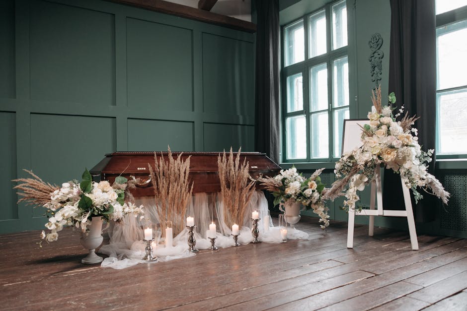 A display of various floral arrangements on black metal shelves inside a glass-walled shop, with natural daylight illuminating the scene. The top shelf features small potted plants and bouquets wrappe